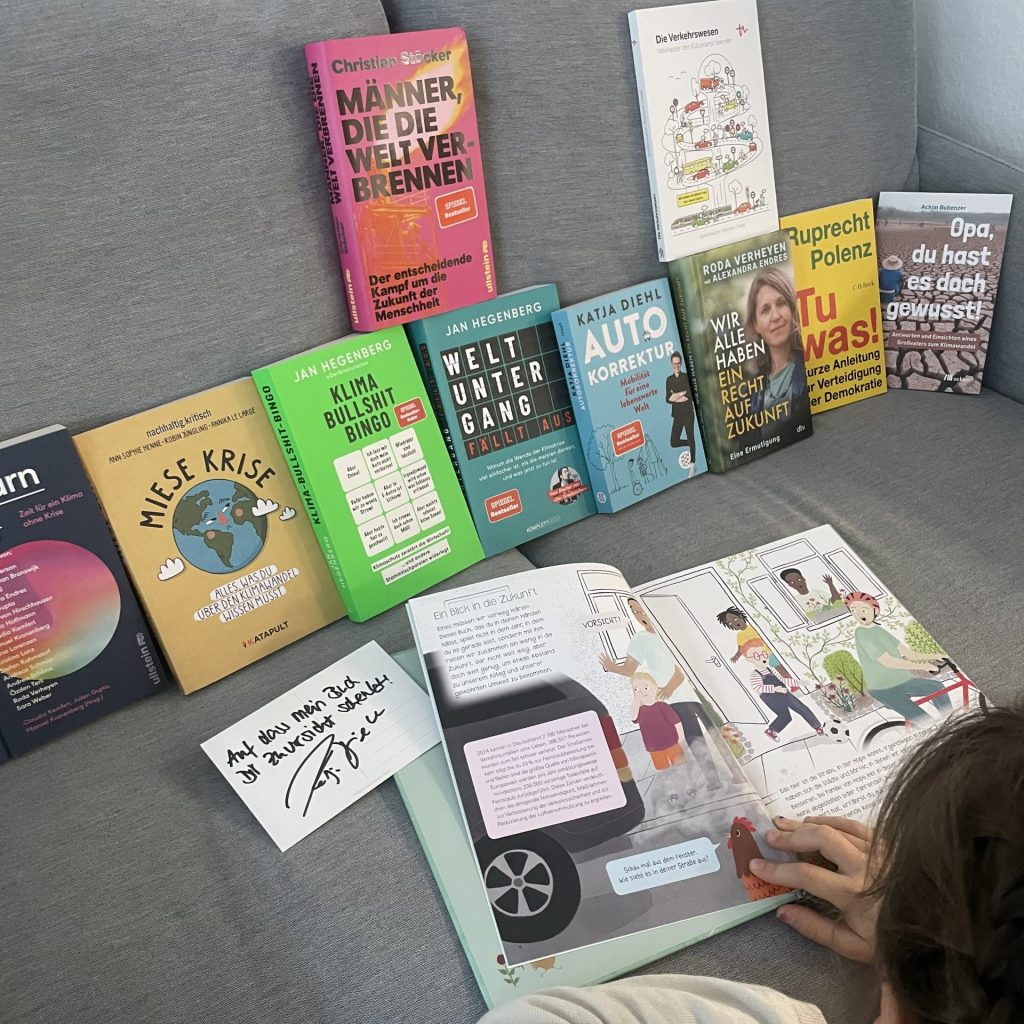 Viele Bücher auf einem Sofa aufgestellt. Ein Kind liest in einem Kinderbuch